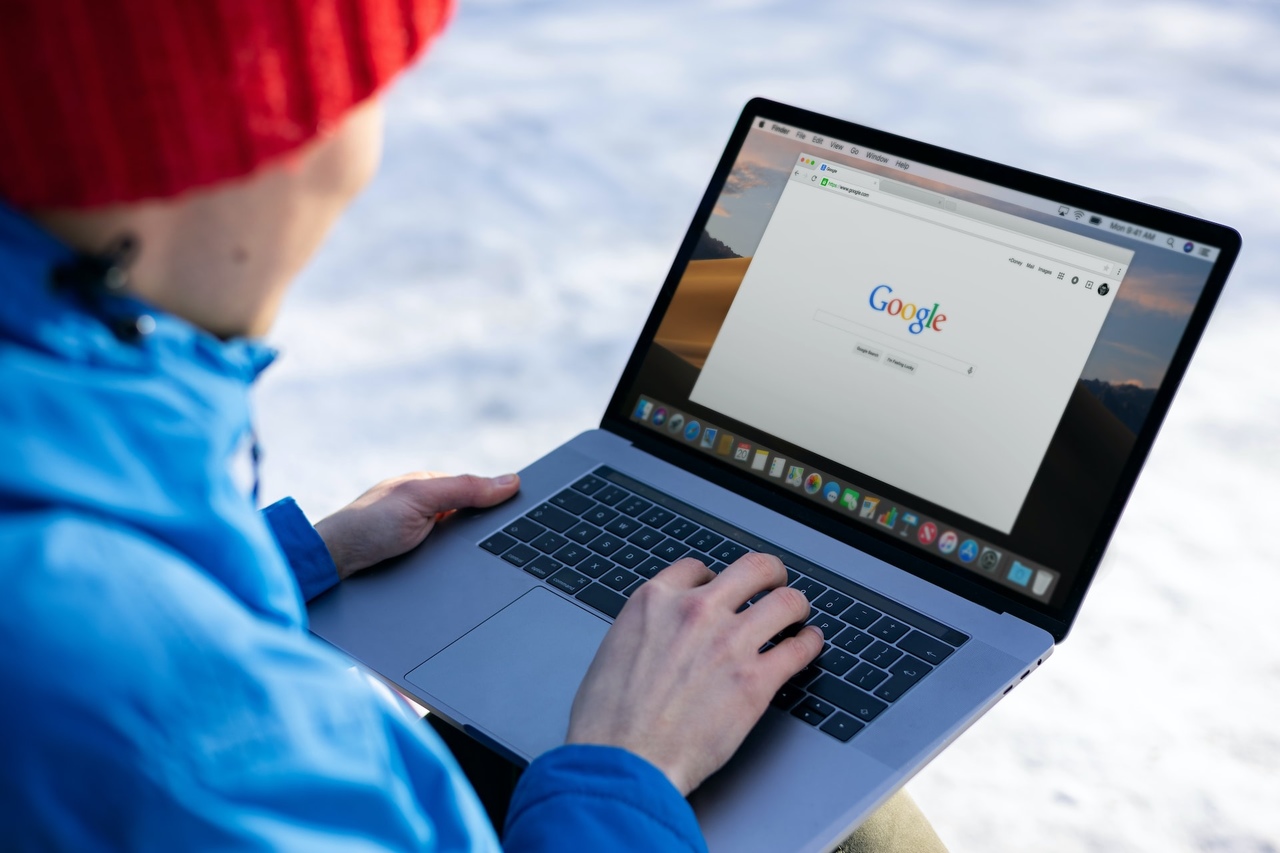 mężczyzna z laptopem na kolanach wpatrujący się w wyszukiwarkę google