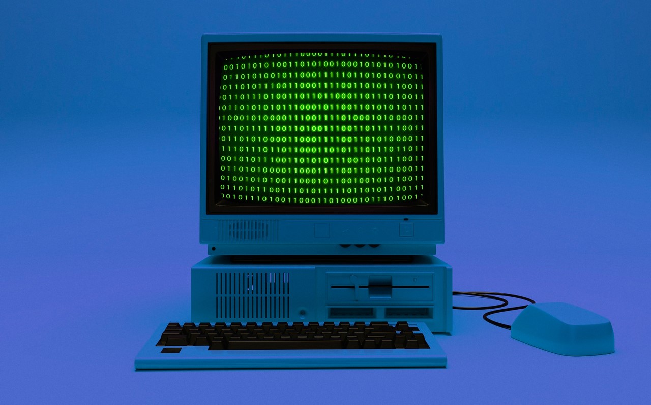 stary komputer, na ekranie znajduje się kod źródłowy wyświetlony na zielono